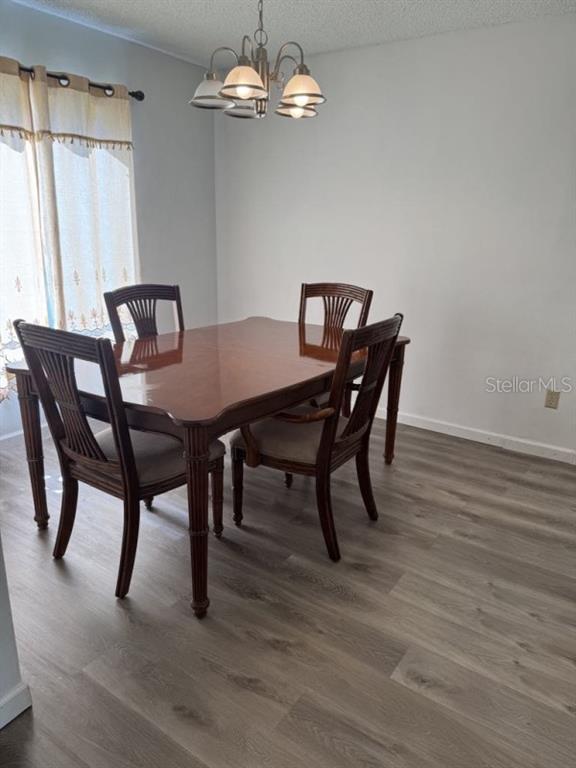 A dining room with a wooden table, four chairs, a chandelier, and light-colored flooring — 5523 WESTVIEW DRIVE, ORLANDO, FL