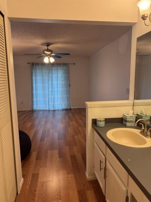 A bathroom vanity with a sink sits adjacent to a living area with wood flooring — 5523 WESTVIEW DRIVE, ORLANDO, FL