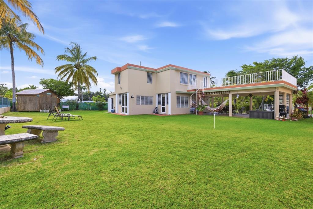 A two-story house with a large lawn, palm trees, and a covered patio area — 610 CALLE VISTAMAR, RIO GRANDE, PR