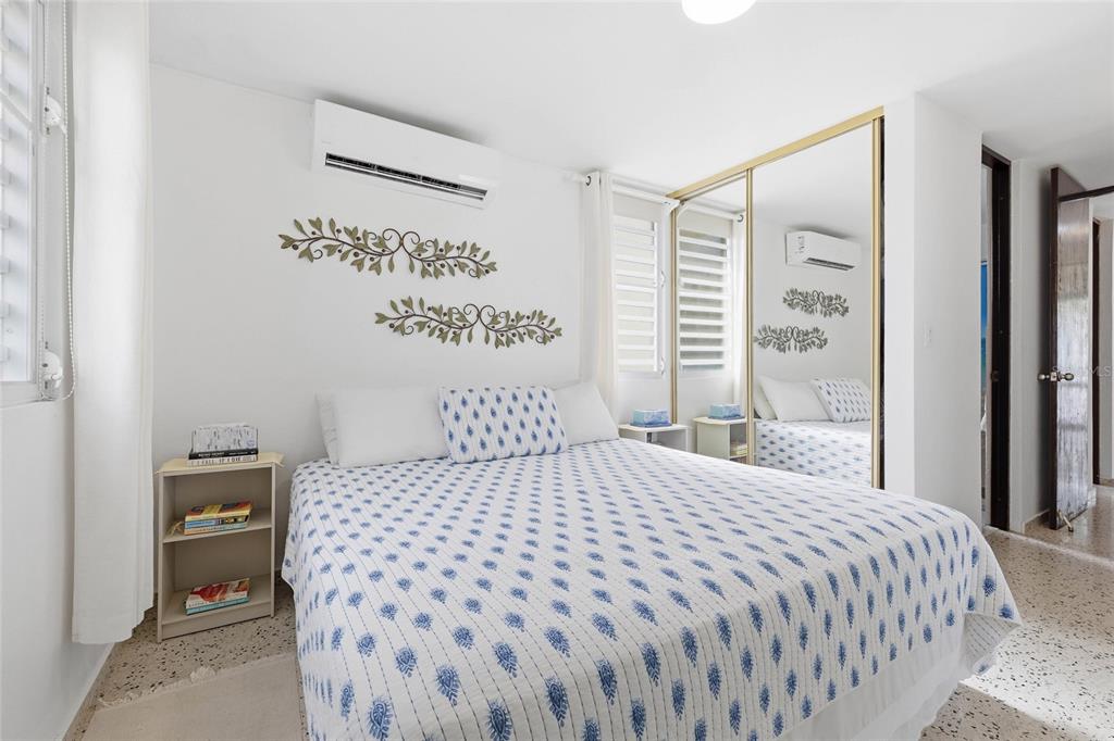 A bedroom features a bed with a patterned quilt, mirrored closet doors, and wall-mounted decor — 610 CALLE VISTAMAR, RIO GRANDE, PR