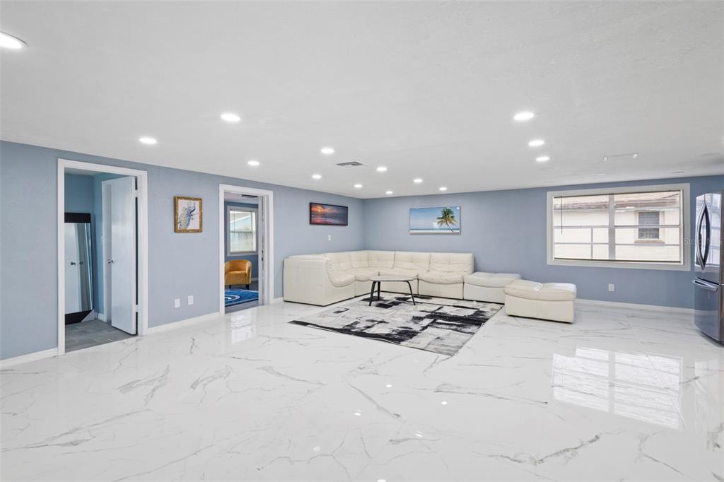 A spacious living room features white marble floors, a white sectional sofa, and recessed lighting — 3332 WILSON DRIVE, HOLIDAY, FL