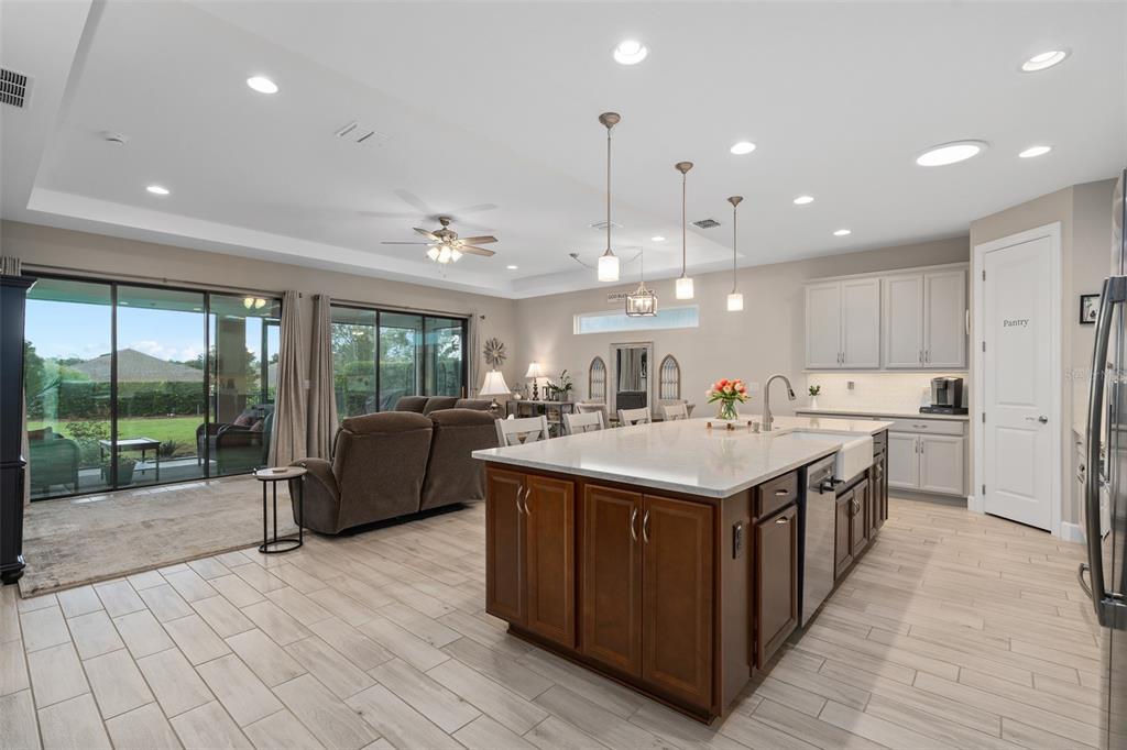 A kitchen with a large wooden island and white countertops opens into a living area — 1389 ZEEK RIDGE STREET, CLERMONT, FL