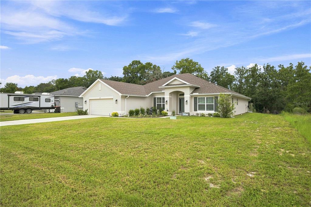 A single-story house with a beige exterior, a two-car garage, and a large front lawn — 5367 SW 150TH LANE, OCALA, FL