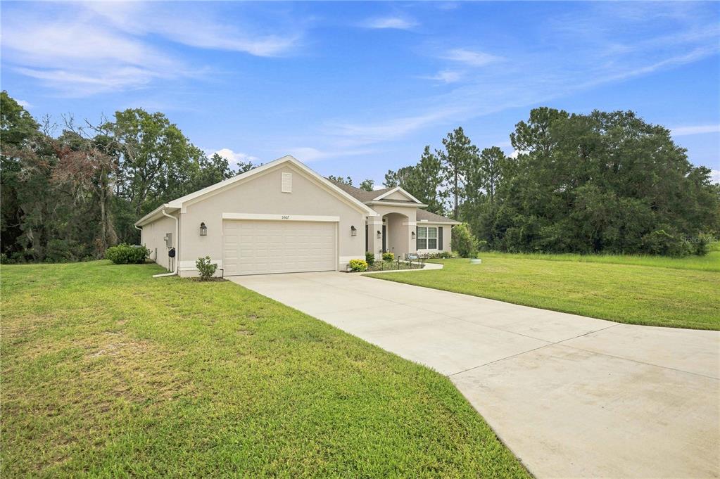 A single-story house with a beige exterior, a two-car garage, and a concrete driveway — 5367 SW 150TH LANE, OCALA, FL