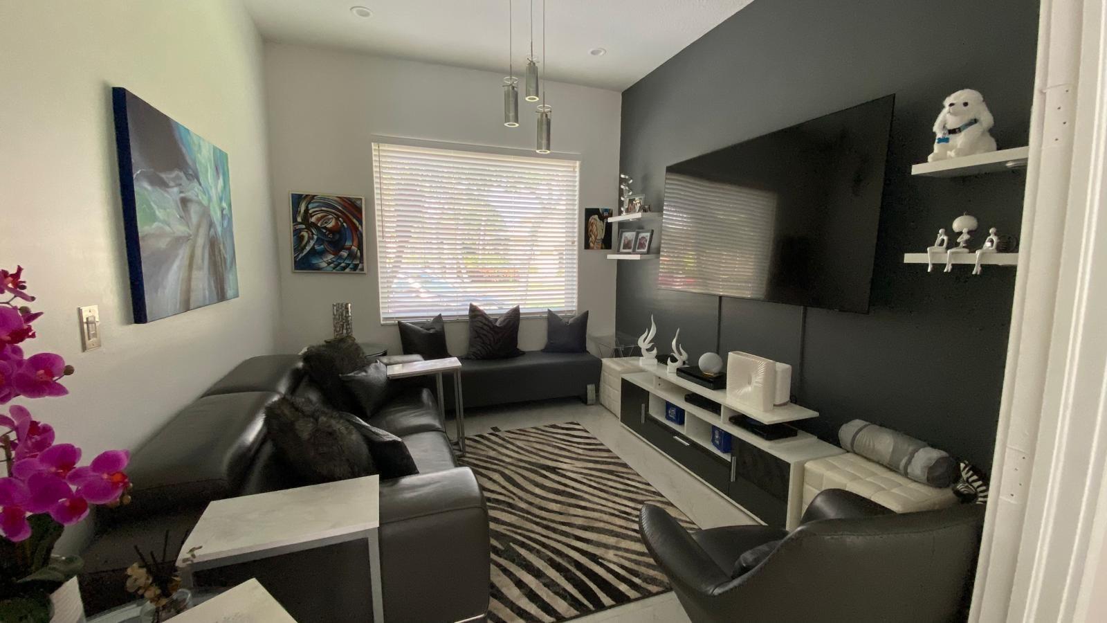 A living room features a black accent wall, a large television, and a zebra-print rug — 830 Bailey Street, Boca Raton FL 33487, BOCA RATON, FL