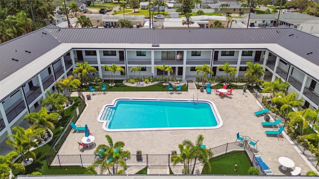 An aerial view of a courtyard featuring a swimming pool surrounded by palm trees and furniture — 2942 W BAY DRIVE UNIT 36, BELLEAIR BLUFFS, FL