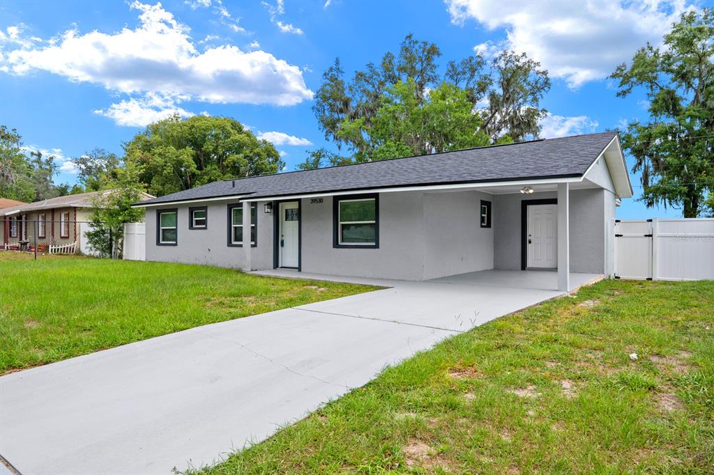 A single-story house with a gray exterior, dark trim, and a concrete driveway — 39530 LINCOLN AVENUE, ZEPHYRHILLS, FL