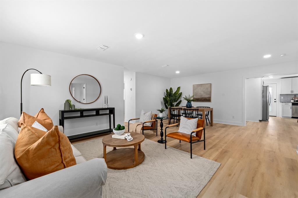 A bright living room features light wood flooring, a neutral area rug, and modern furniture — 39530 LINCOLN AVENUE, ZEPHYRHILLS, FL