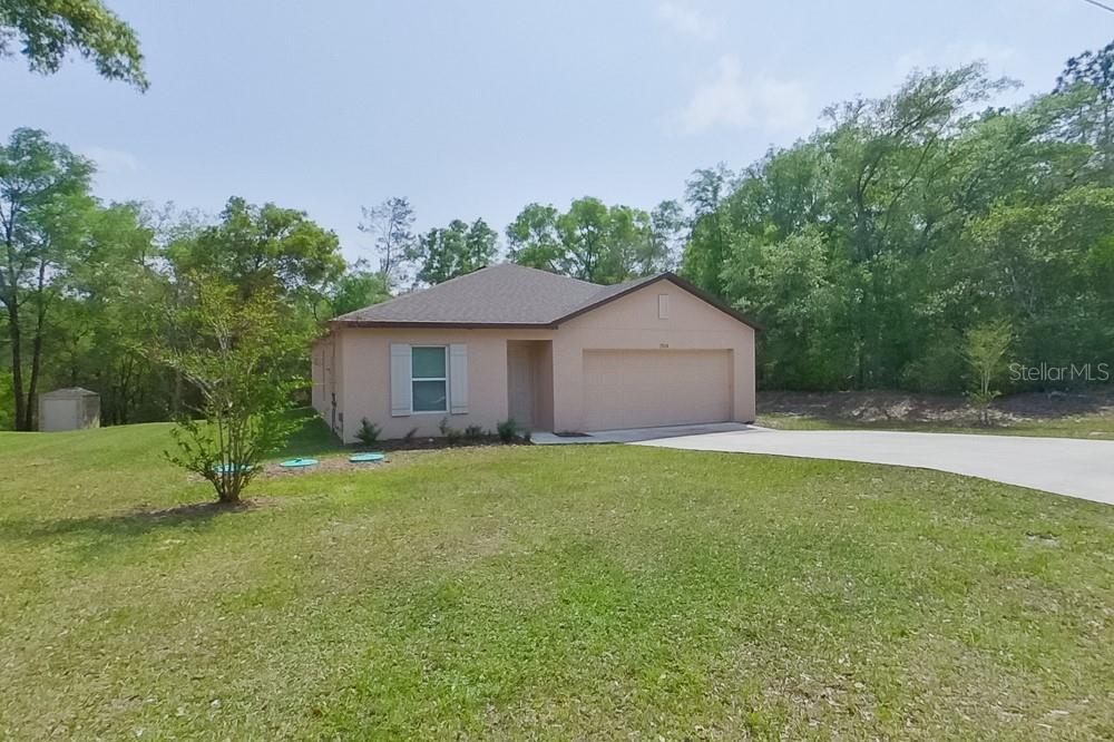 A single-story house with a beige exterior, a two-car garage, and a large grassy yard — 1924 W ROSEBORO DRIVE, DUNNELLON, FL