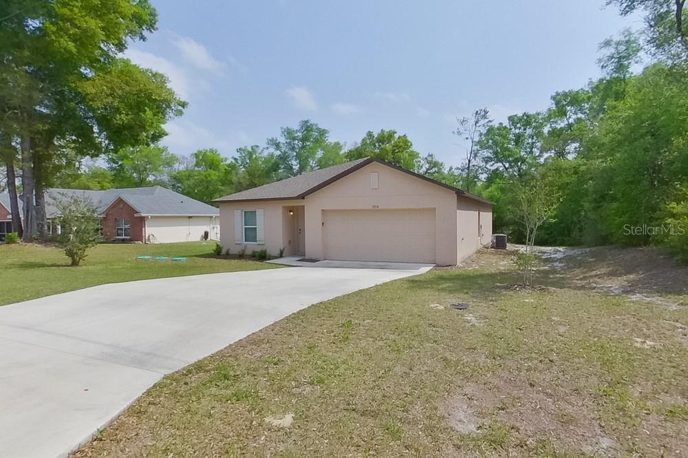 A single-story house with a beige stucco exterior, a two-car garage, and a concrete driveway — 1924 W ROSEBORO DRIVE, DUNNELLON, FL