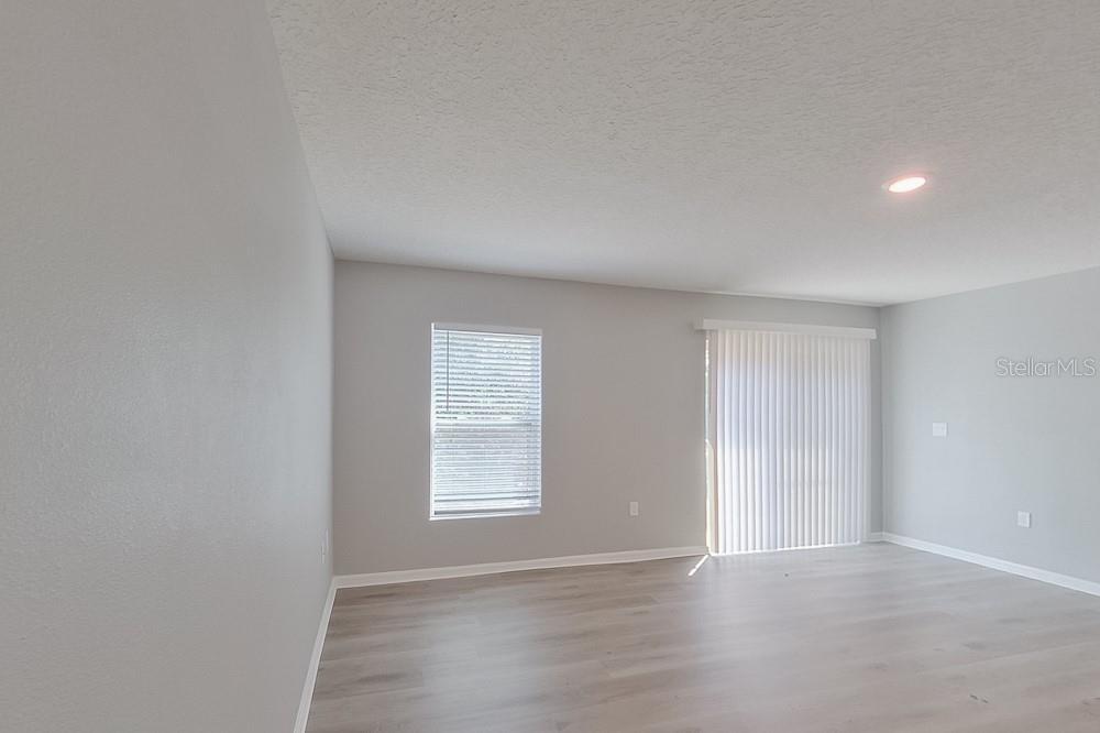 An empty room with light gray walls, wood-look flooring, a window, and sliding glass doors — 1924 W ROSEBORO DRIVE, DUNNELLON, FL