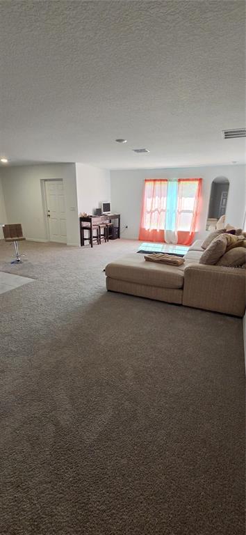 A spacious living room features beige carpeting, a large sectional sofa, and a desk area — 558 TASCO AVENUE SW, PALM BAY, FL