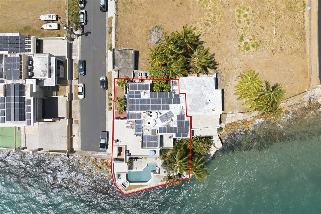 An aerial view shows a waterfront house with solar panels and a pool — 4 EMAJAGUA, SAN JUAN, PR