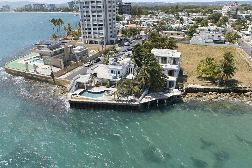 An aerial view shows two waterfront houses with pools and private docks along the coast — 4 EMAJAGUA, SAN JUAN, PR