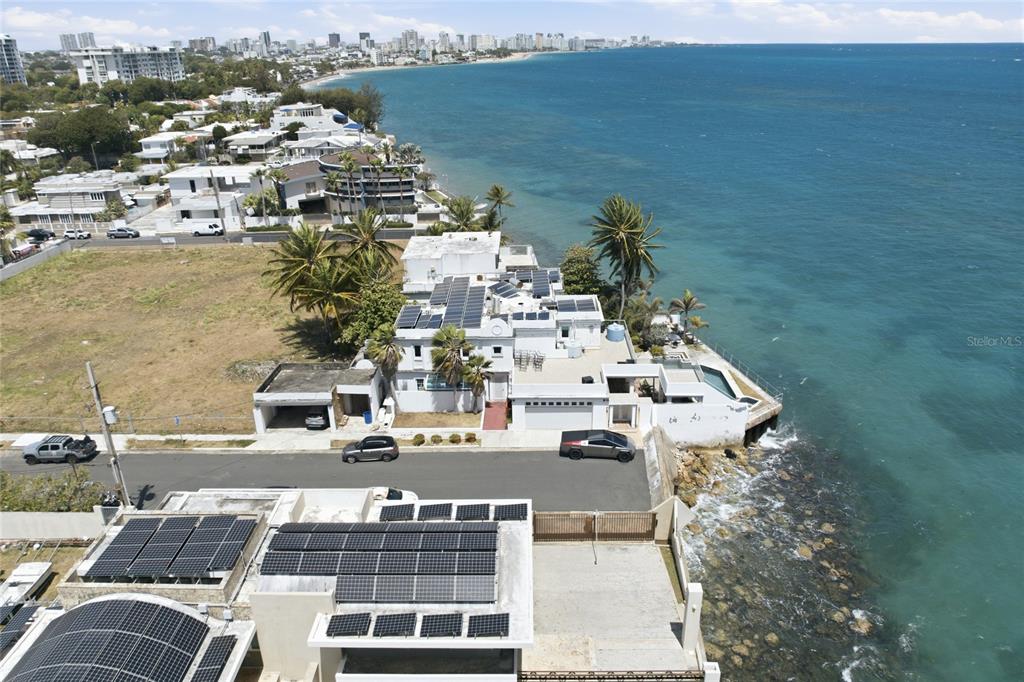 An aerial view shows a coastal property with solar panels, a pool, and oceanfront access — 4 EMAJAGUA, SAN JUAN, PR