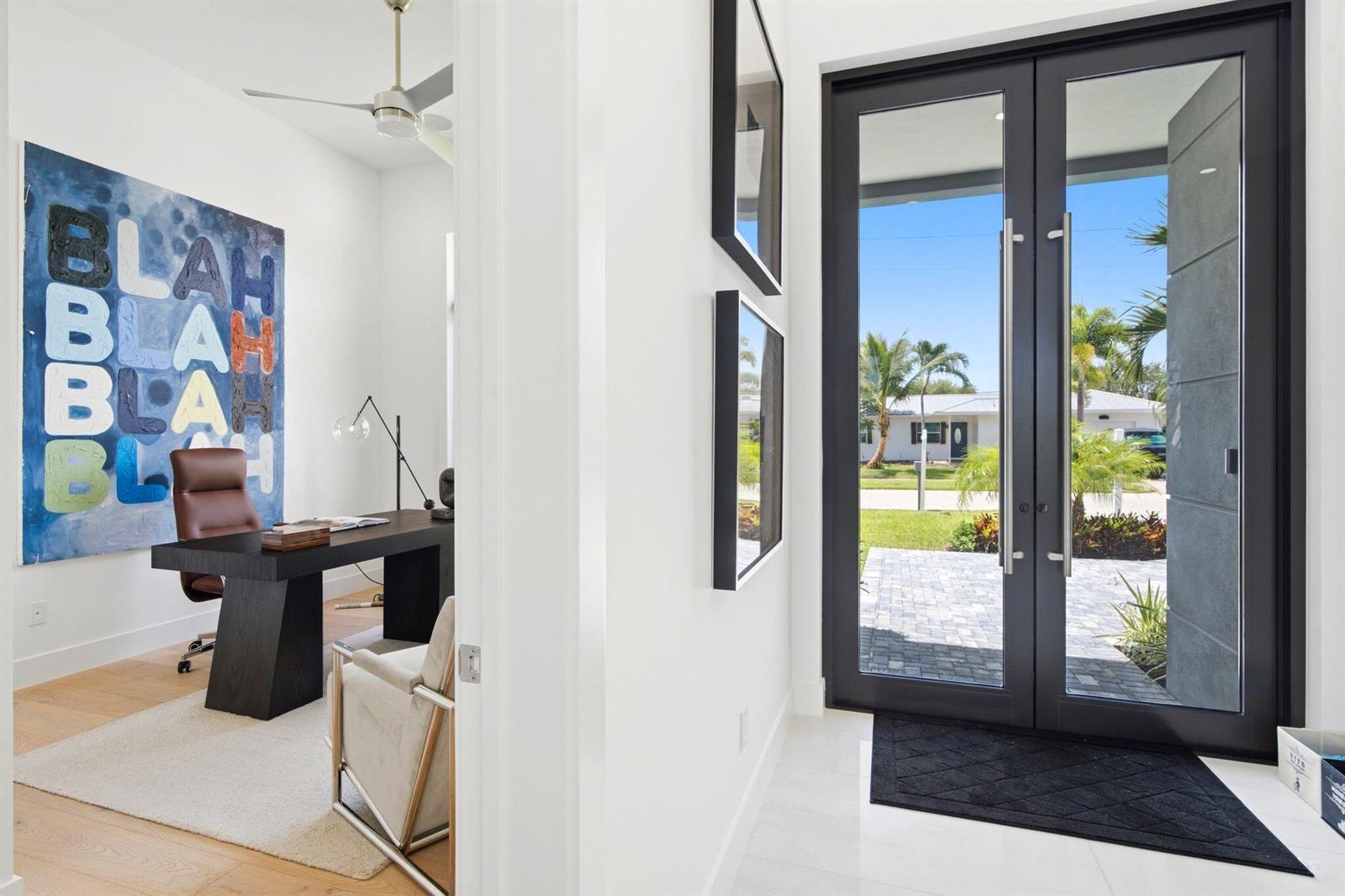 A home office with a dark desk and large art piece sits beside an entryway — 261 NW 8th Street, Boca Raton FL 33432, BOCA RATON, FL