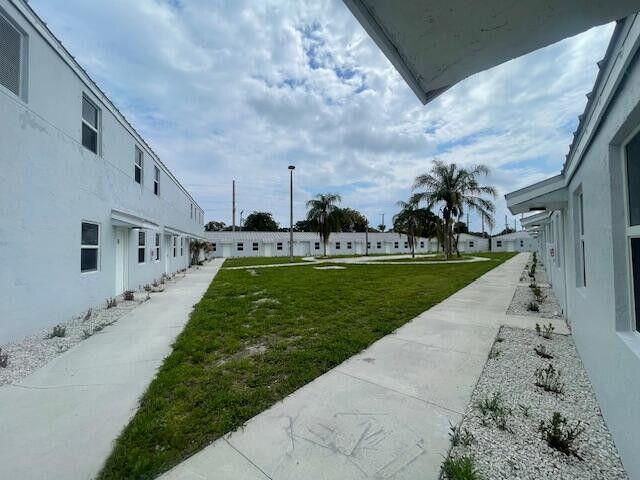 A courtyard with a green lawn sits between two white apartment buildings under a cloudy sky — 4393 Windsor Avenue # 4, West Palm Beach FL 33407, WEST PALM BEACH, FL