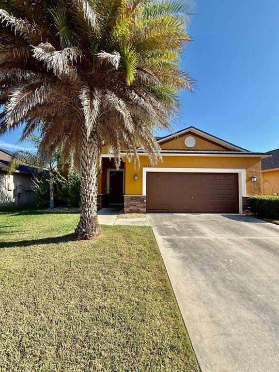 A two-story house with yellow stucco walls, a brown garage door, and stone accents — 12404 BALLENTRAE FOREST DRIVE, RIVERVIEW, FL