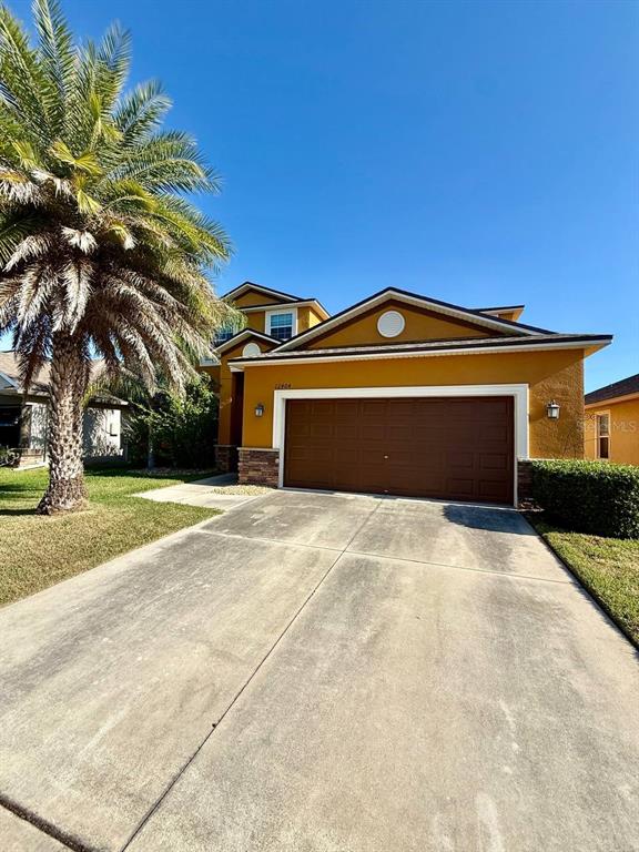 A tan house exterior features a brown two-car garage door and a palm tree — 12404 BALLENTRAE FOREST DRIVE, RIVERVIEW, FL