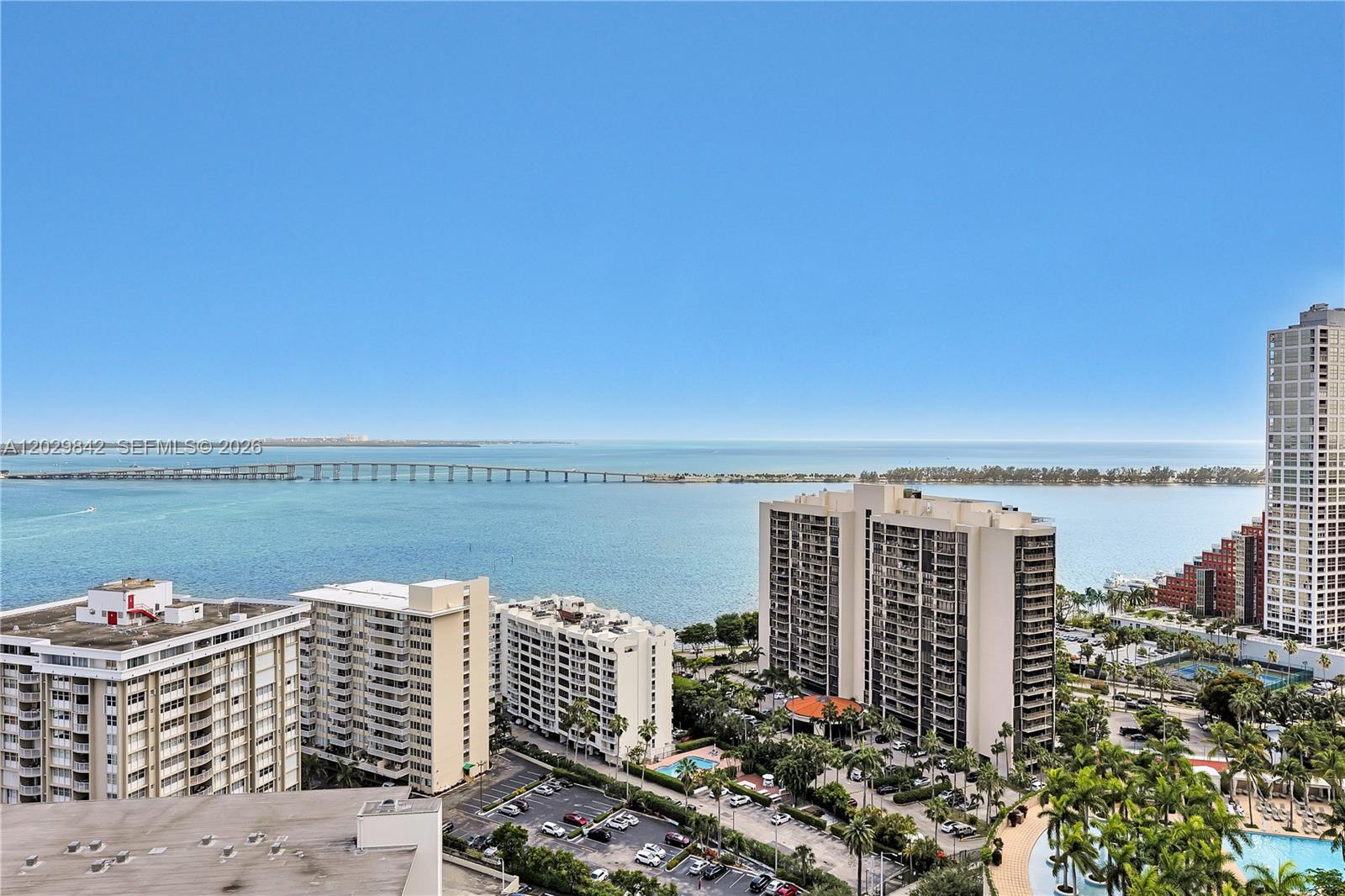 An elevated view shows multiple high-rise apartment buildings overlooking a bay and a long bridge — 218 SE 14th St, Miami FL 33131, MIAMI, FL