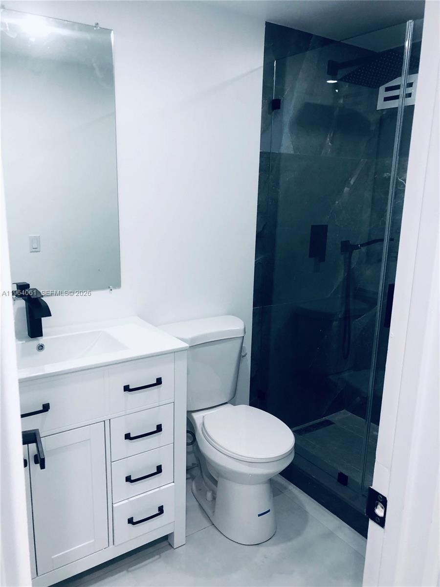 A modern bathroom features a white vanity, a toilet, and a glass-enclosed walk-in shower — 10185 Collins Ave # 209, Bal Harbour FL 33154, BAL HARBOUR, FL