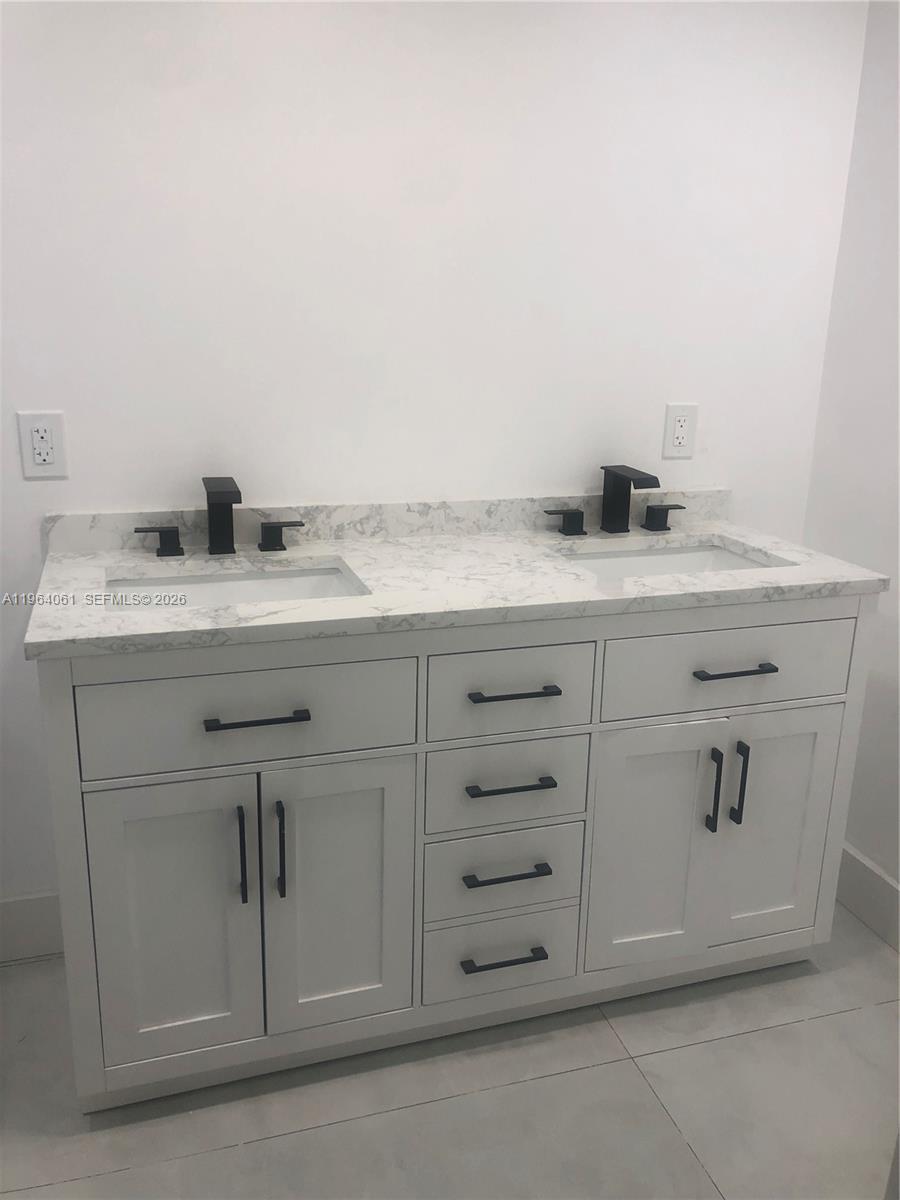 A double-sink bathroom vanity features white cabinetry, black hardware, and a white marble countertop — 10185 Collins Ave # 209, Bal Harbour FL 33154, BAL HARBOUR, FL