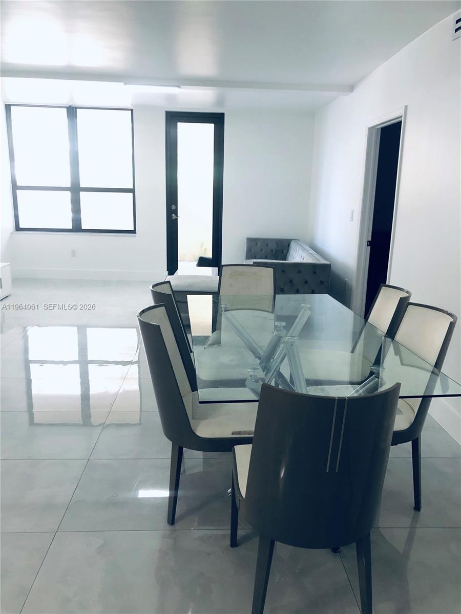 A dining area with a glass table and chairs sits in front of a living space — 10185 Collins Ave # 209, Bal Harbour FL 33154, BAL HARBOUR, FL