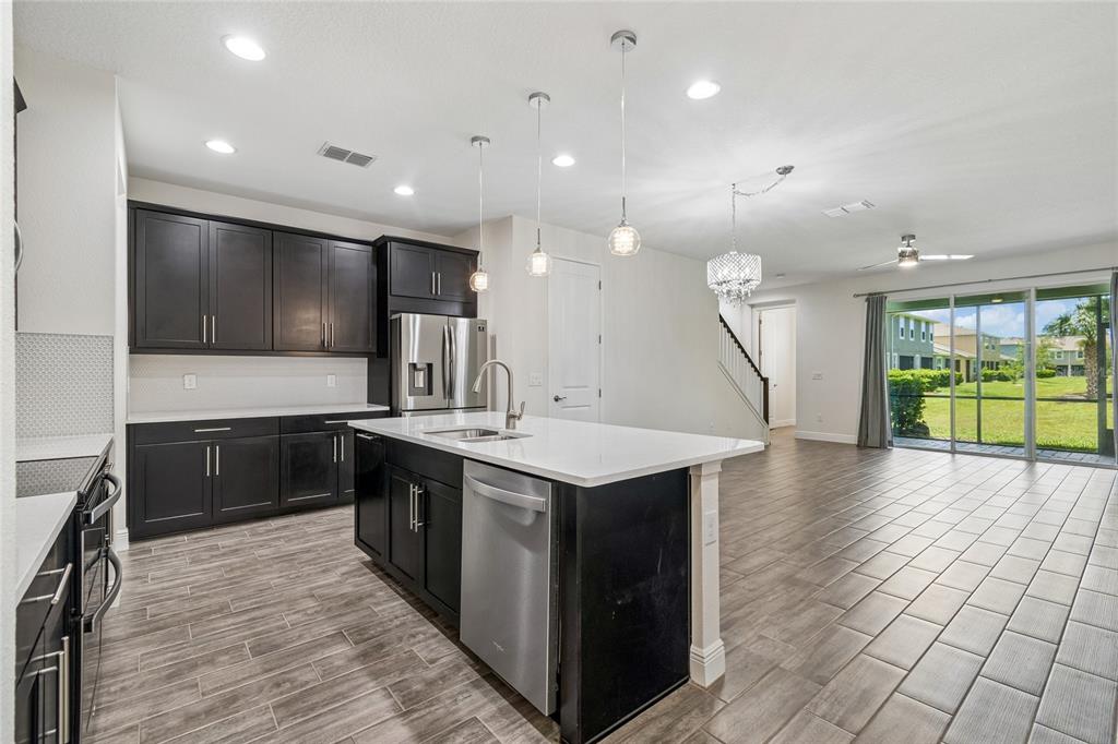 A kitchen with dark cabinets, a white island, and tile flooring opens to a living area — 2410 ARCH AVENUE, OLDSMAR, FL