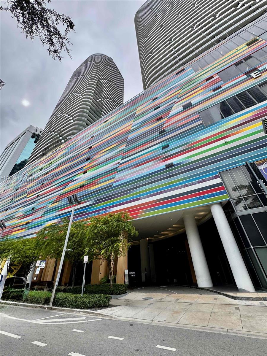A low-angle exterior view of a modern building with a colorful, horizontally striped facade — 55 SW 9th St # 3201, Miami FL 33130, MIAMI, FL