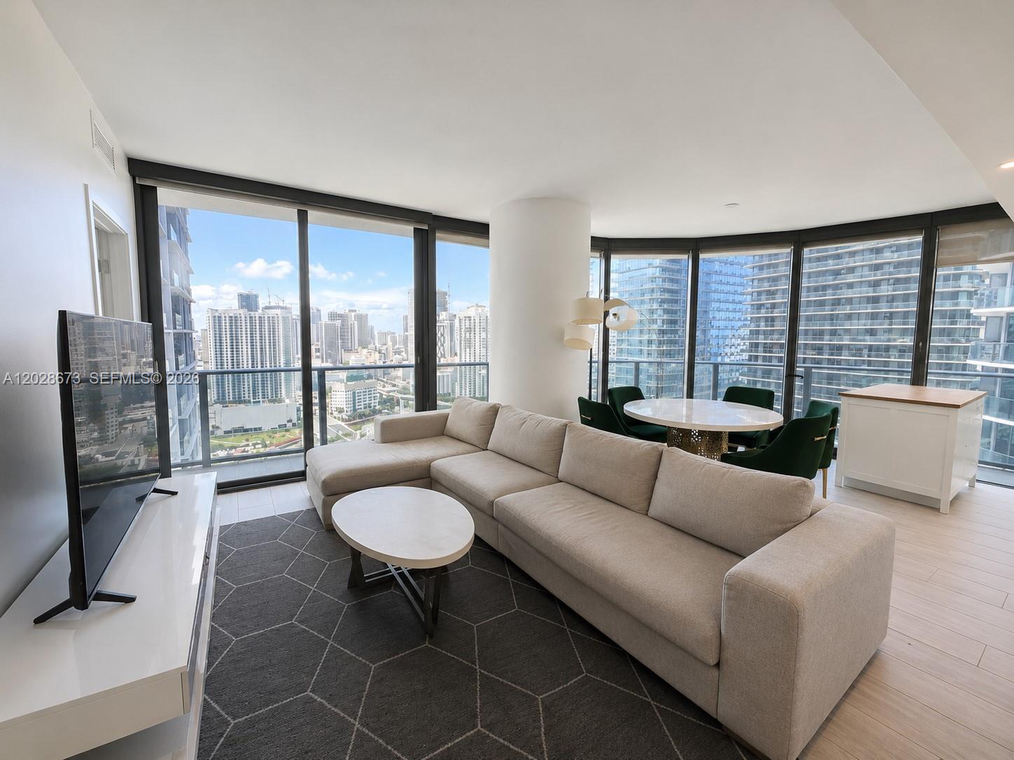 A modern living room features a beige sectional sofa, a round coffee table, and floor-to-ceiling windows — 55 SW 9th St # 3201, Miami FL 33130, MIAMI, FL