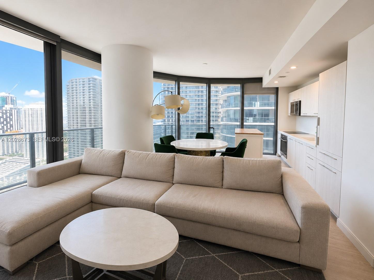 A modern living room features a beige sectional sofa, a dining area, and floor-to-ceiling windows — 55 SW 9th St # 3201, Miami FL 33130, MIAMI, FL