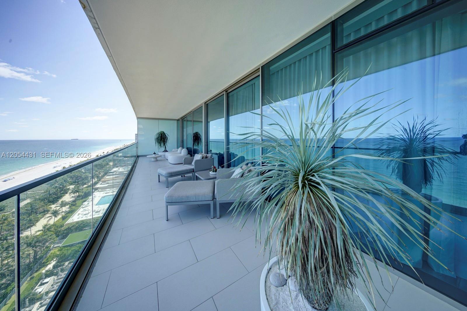 A spacious balcony with outdoor furniture overlooks the ocean and a beach — 10203 Collins Ave # 1502, Bal Harbour FL 33154, BAL HARBOUR, FL