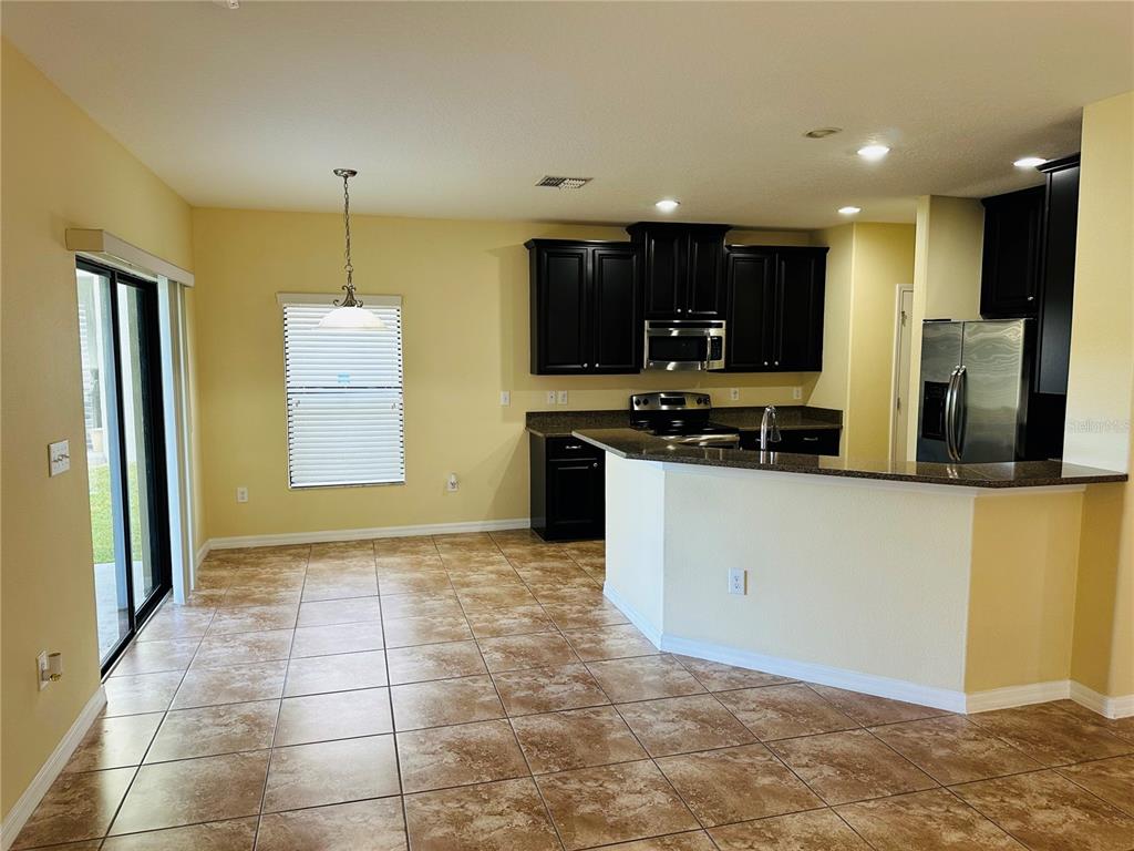 A kitchen with dark cabinets and a breakfast bar overlooks a tiled dining area — 9908 SPICE BUSH COURT, TAMPA, FL