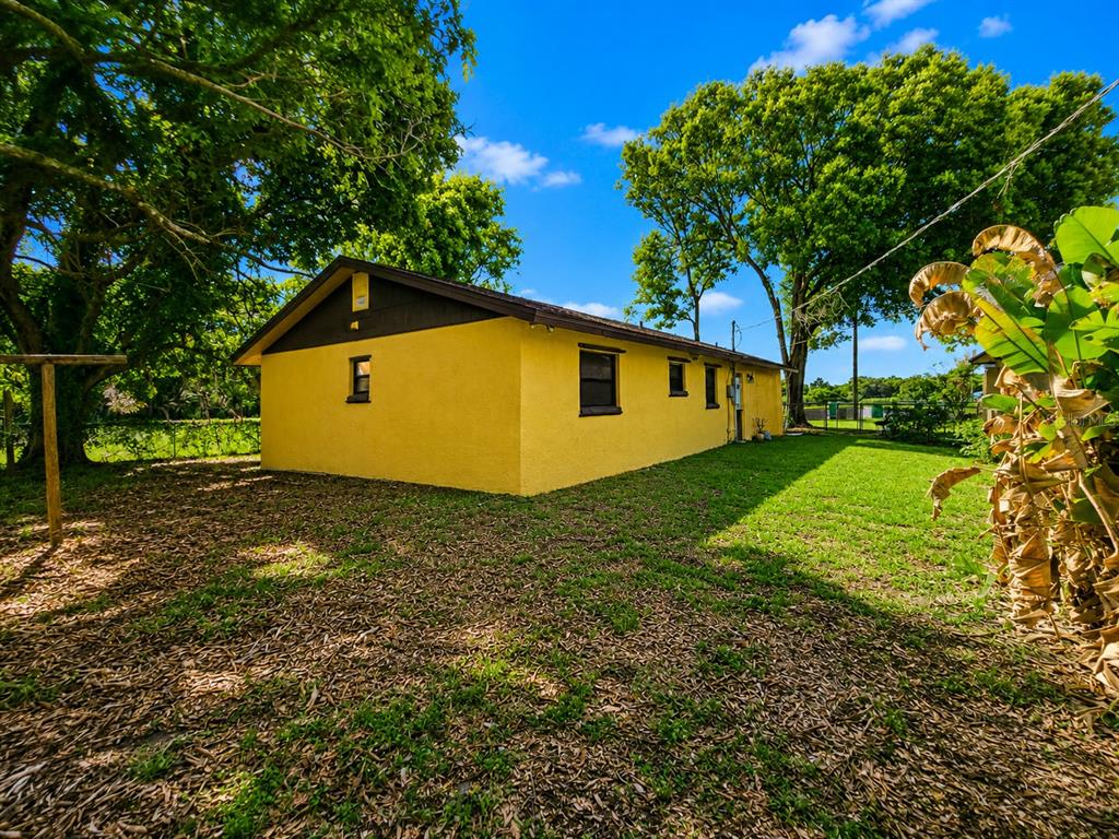 A yellow house with a brown roof stands in a grassy yard with large trees — 3300 JAMES STREET, MELBOURNE, FL