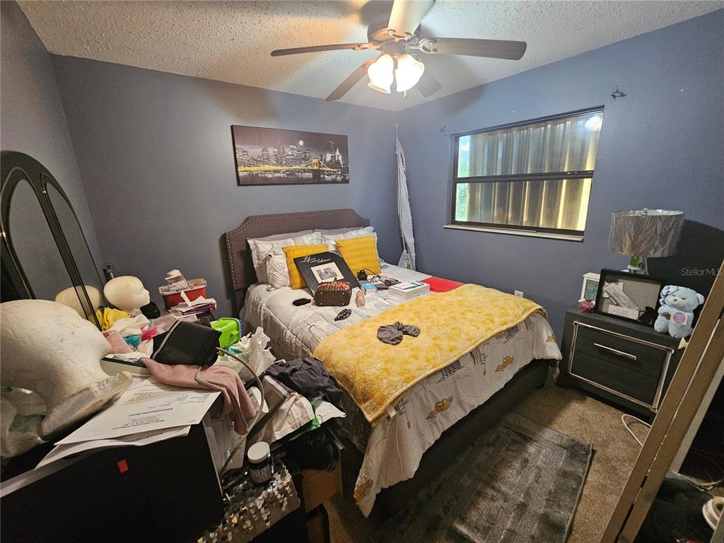 A bedroom features a bed with yellow bedding, a ceiling fan, and dark blue walls — 3300 JAMES STREET, MELBOURNE, FL