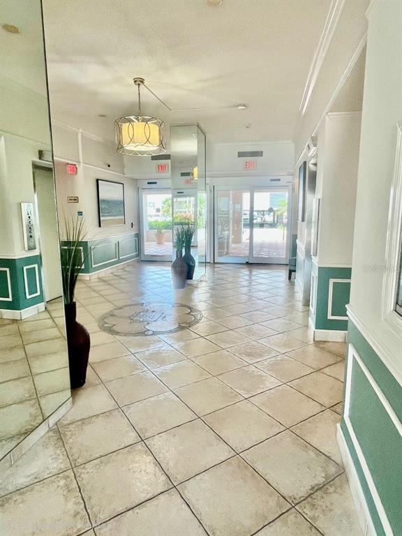 A bright building lobby features tiled floors, a decorative medallion, and glass sliding entry doors — 851 BAYWAY BOULEVARD UNIT 405, CLEARWATER BEACH, FL