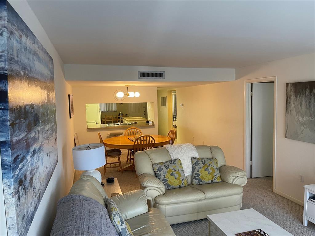 A living room with beige leather furniture leads to a dining area and kitchen pass-through — 106 1ST STREET E UNIT 210, TIERRA VERDE, FL