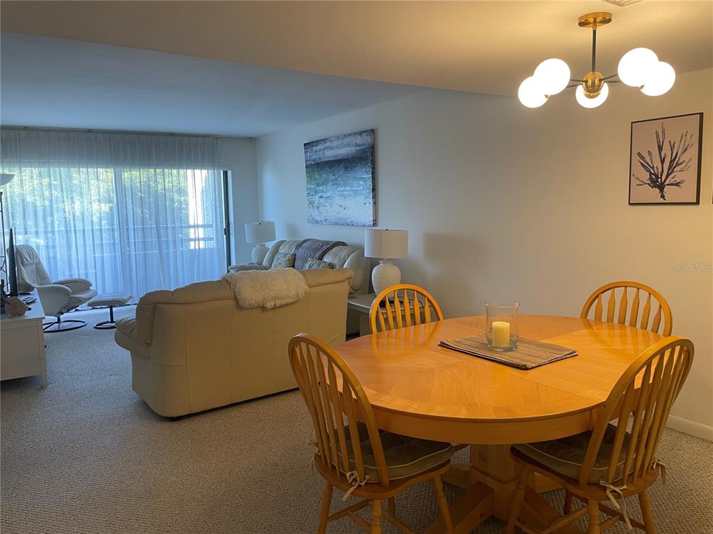 A dining area with a wooden table and chairs sits in front of a living room — 106 1ST STREET E UNIT 210, TIERRA VERDE, FL