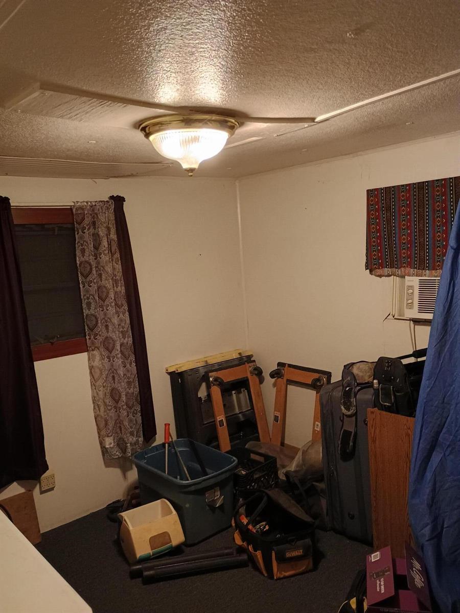 A cluttered room with a ceiling light, a window with curtains, and a wall air conditioner — 1512 NE Dove Avenue, Stuart FL 34994, STUART, FL