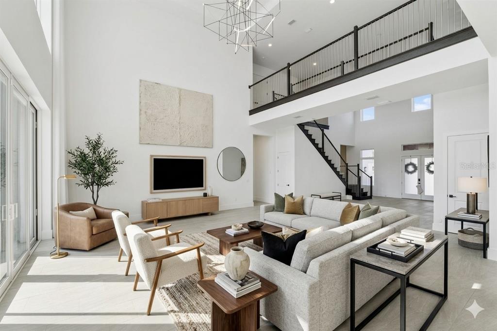 A spacious, high-ceilinged living room features a large sectional sofa, modern furniture, and a staircase — 9720 LAUREL BERRY DRIVE, ORLANDO, FL