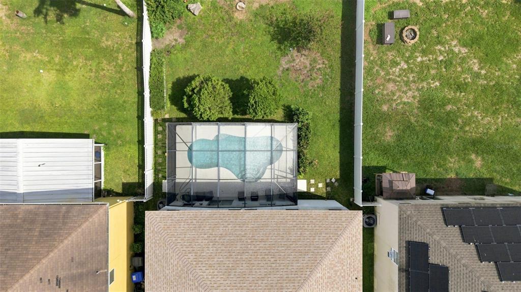 An aerial view shows a house with a screened-in pool and a fenced backyard — 4563 PHILADELPHIA CIRCLE, KISSIMMEE, FL