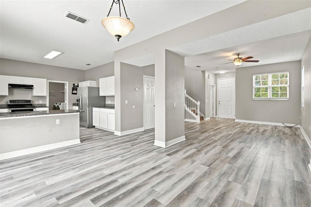 An open-concept living area features light gray walls, wood-look flooring, and a kitchen with white cabinets — 4563 PHILADELPHIA CIRCLE, KISSIMMEE, FL