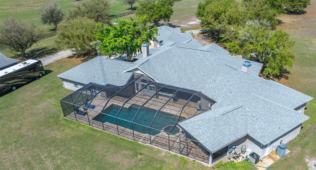 An aerial view of a house with a screened-in pool and a parked recreational vehicle — 11939 PASCO TRAILS BOULEVARD, SPRING HILL, FL