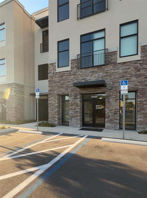 The exterior of a multi-story building features stone veneer, glass doors, and two handicap parking signs — 13564 VILLAGE PARK DRIVE UNIT 375, ORLANDO, FL