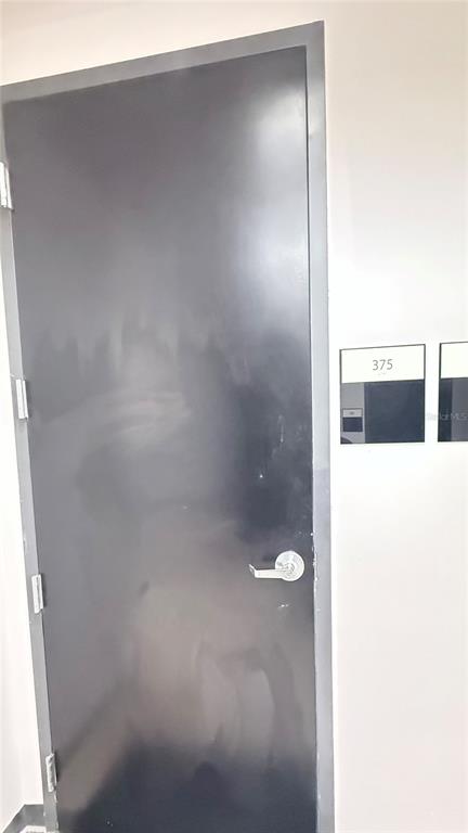 A dark-colored door with a silver handle is labeled with the number 375 — 13564 VILLAGE PARK DRIVE UNIT 375, ORLANDO, FL