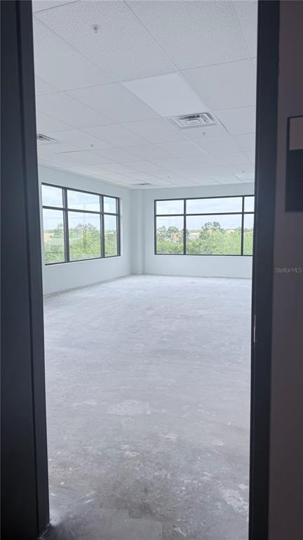 An empty office space with large windows, a drop ceiling, and unfinished concrete flooring — 13564 VILLAGE PARK DRIVE UNIT 375, ORLANDO, FL