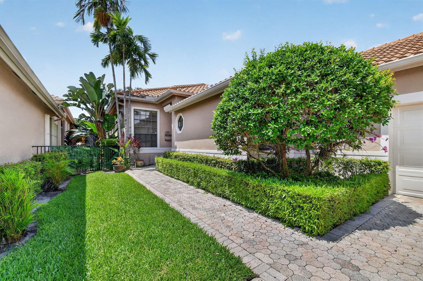 A paved walkway leads to the entrance of a house with a manicured hedge — 4548 Barclay Fair Way, Lake Worth FL 33449, LAKE WORTH, FL