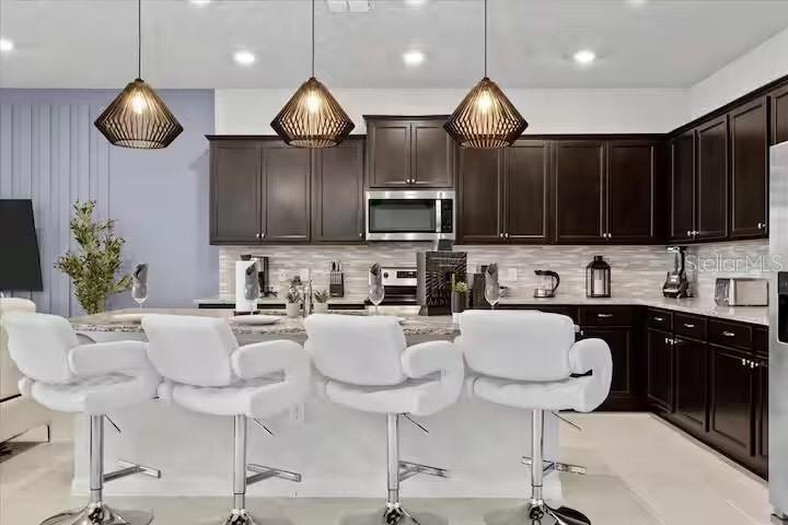 A kitchen features dark wood cabinets, white countertops, three pendant lights, and white bar stools — 2190 LELANI CIRCLE, DAVENPORT, FL