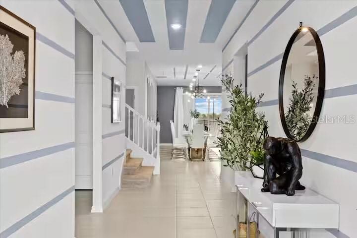A hallway with striped walls leads to a dining area featuring a staircase and mirror — 2190 LELANI CIRCLE, DAVENPORT, FL