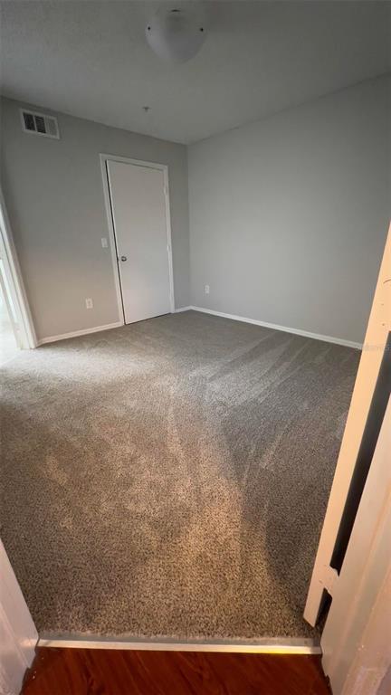 An empty bedroom features gray walls, beige carpet, and a single white interior door — 2206 ANTIGUA PLACE UNIT 1037, KISSIMMEE, FL